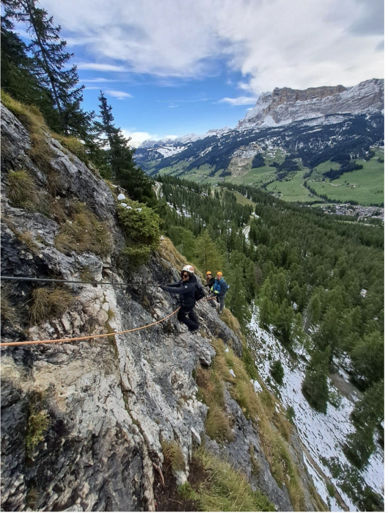 A group of people climbing a mountainside in the Dolomites on a summer day in Italy.